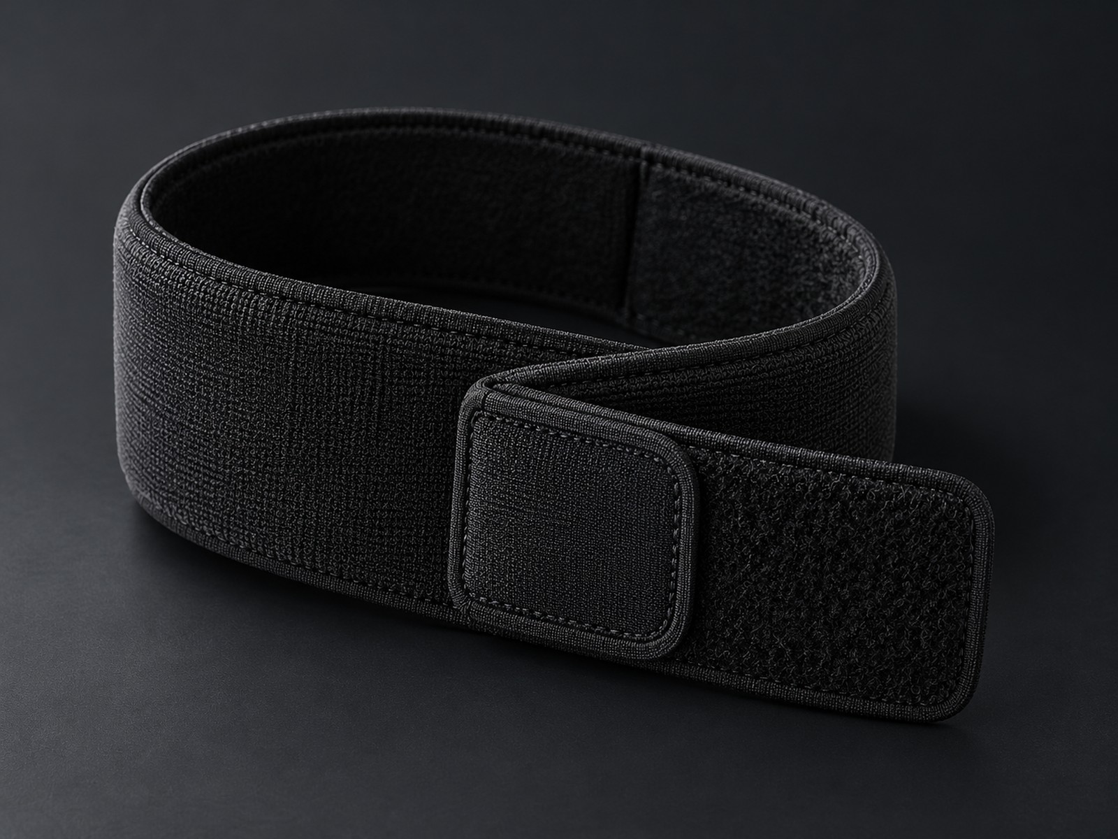 Loosely coiled matte black Universal Wrap with its adjustable fastener visible.